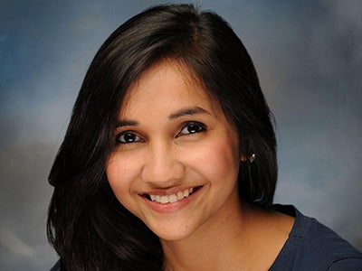 A headshot shows Kinni Shah smiling in front of a blue backdrop. 