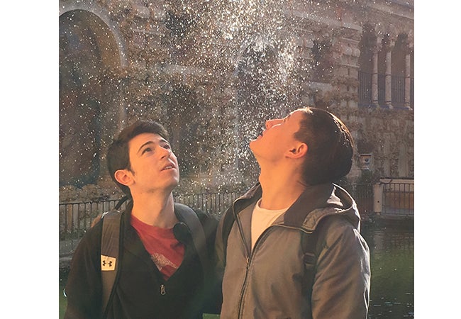 Two students stand beside each other and look up during light precipitation during a study abroad trip in Spain.