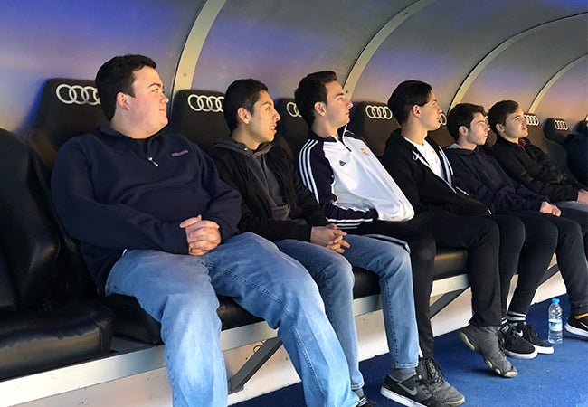 A group of students sit in jet black stadium seats during a facility tour while studying abroad in Spain. 