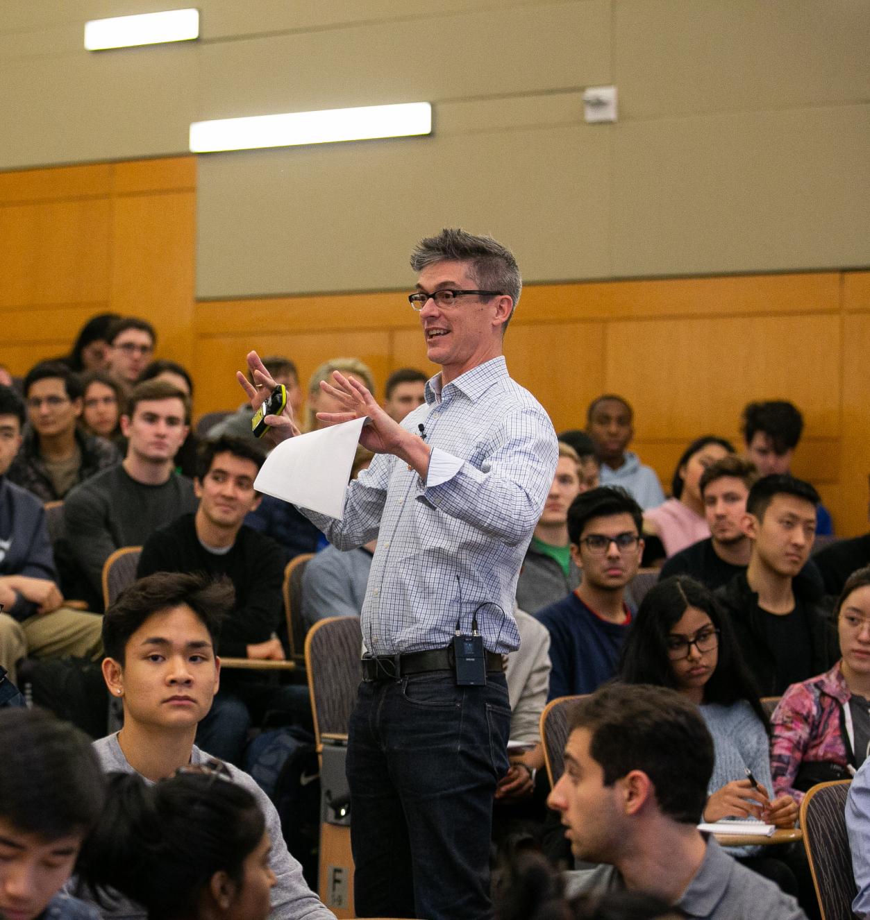 Professor speaking while standing in a crowd of seated students