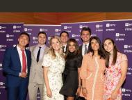 Group of EMBA students pose in front of step and repeat