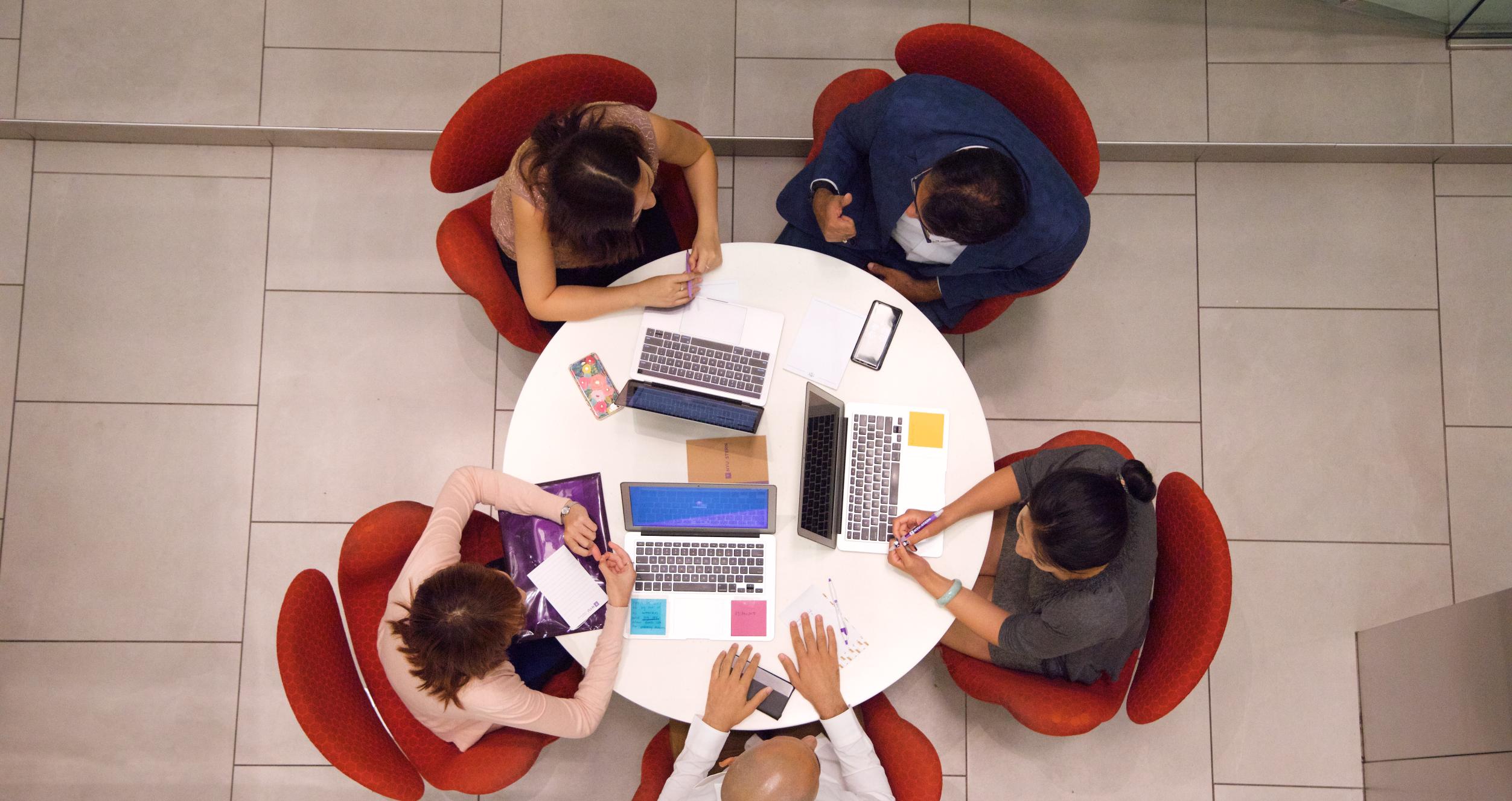 Students around a circular table with laptops
