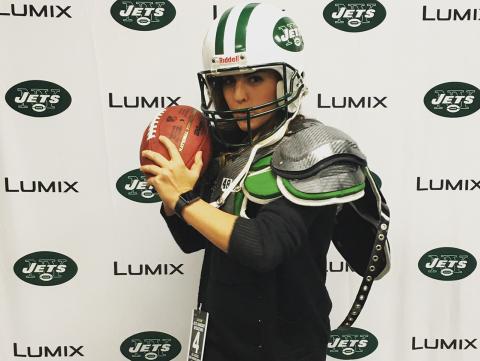 Katherine Davis dressed up in Jets football team gear posing with a football