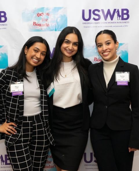 USWIB students pose in front of conference step and repeat