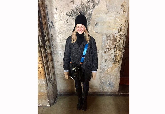 MBA student Elizabeth Cooke stands in a faded entryway to Prague Castle and smiles during a study abroad trip. 