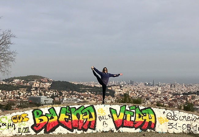 MBA student Elizabeth Cooke balances on one foot while standing in front of a scenic view of Barcelona.