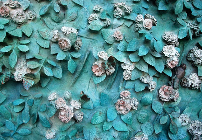 A smattering of teal-colored leaves dotted with white and pink flowers on the door at La Sagrada Familia.