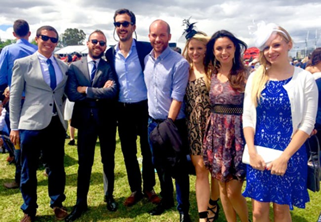 MBA student Cara Witt-Landefeld gathers with friends wearing formal dress for a group photo at an outdoor event. 