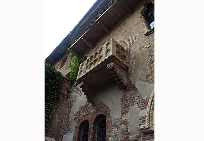 A stone balcony juts out from a faded brick wall in Verona.