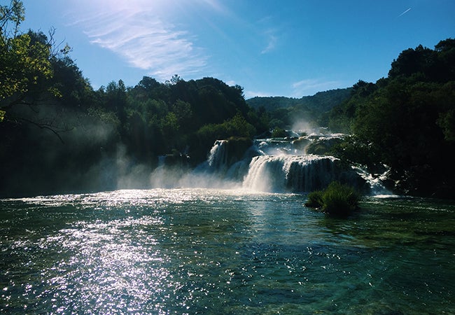 Water cascades over multiple levels of rocks and into a beautiful lake in Kyrka National Park. 