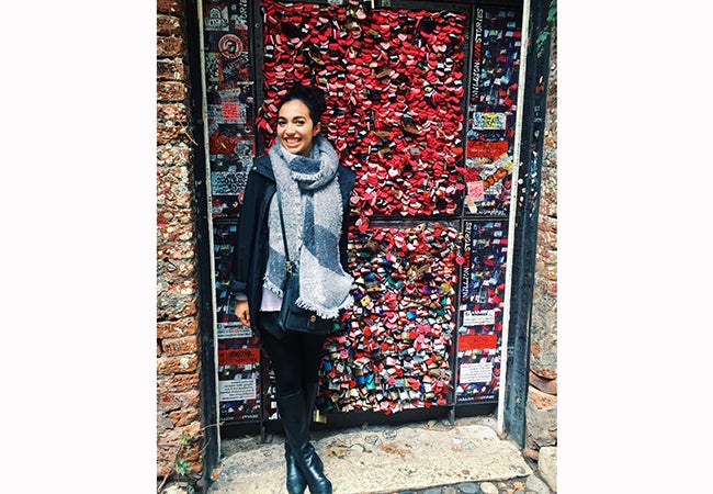 Undergraduate business student Alexandra Grieco stands in front of a wall festooned with red and pink objects.