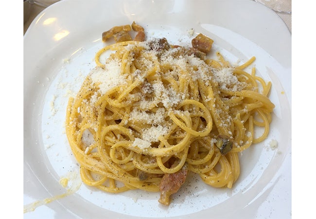 A close-up of a dish of carbonara pasta sprinkled with cheese and served in Rome, Italy. 