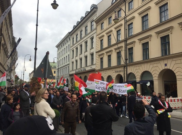 Participants wave flags and signs while marching down a city street in Germany. 