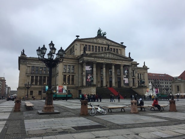 A red carpet lines the steps of a city building in Germany, which sits on the edge of a large courtyard. 