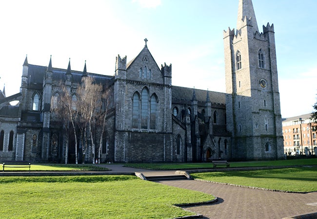 A grand stone building on the grassy campus of Trinity College in Ireland. 