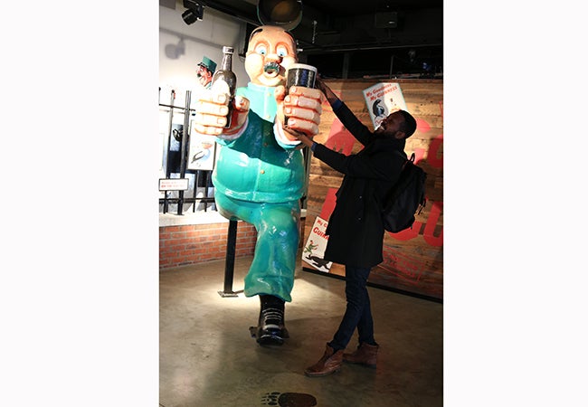 MBA student Calvin Mack acts as if he is taking a beer away from a large cartoonish character installed at Guinness Storehouse.