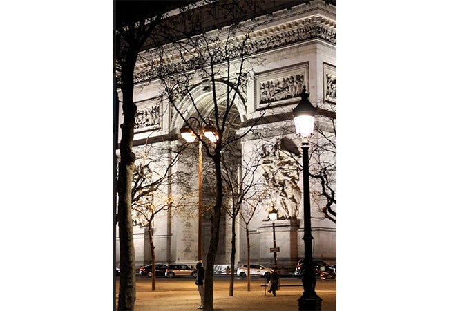 Cars circle the Arc de Triomphe at night in Paris. 