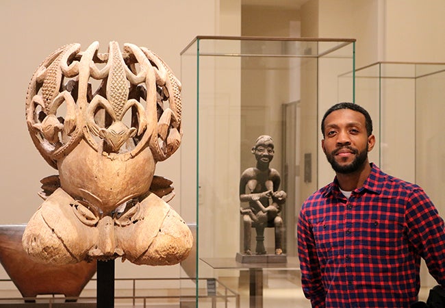 MBA student Calvin Mack stands in front of ancient artifacts on display at the Louvre.