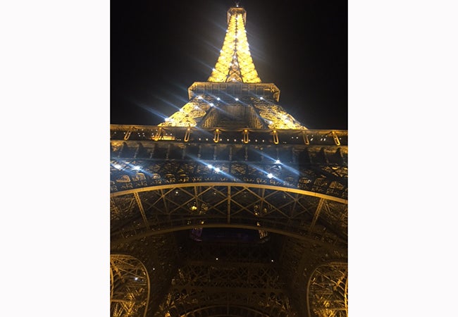 A view of the illuminated Eiffel Tower at night, if looking up from below. 