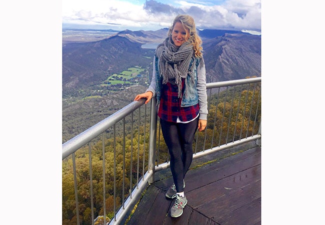 MBA student Cara Witt-Landefeld rests one hand on a fence while taking in the beautiful mountain views in Australia.