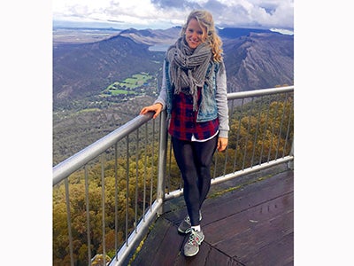 MBA student Cara Witt-Landefeld rests one hand on a fence while taking in the beautiful mountain views in Australia.