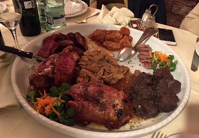 Local Italian meats including venison and wild boar are arranged on a white plate at dinner. 