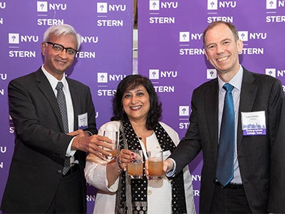 Dean Sundaram, Dean Menon, and Vice Dean Whitelaw smile and clink glasses