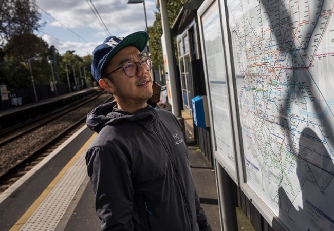 MBA student Dennis Au examines a public transit map at an outdoor stop. 