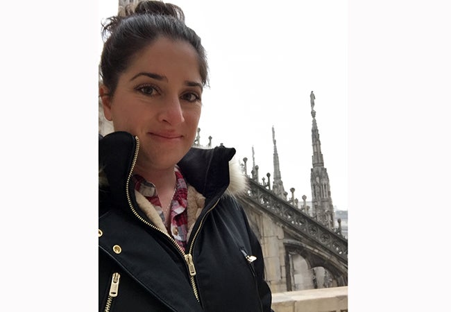 MBA student Ashley Grand, dressed in cold-weather gear, stands before beautiful stonework at the Duomo in Milan. 