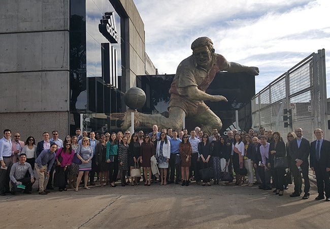 Executive MBA students pose in front of a large sculpture of a figure kicking a ball during their travels in Argentina.