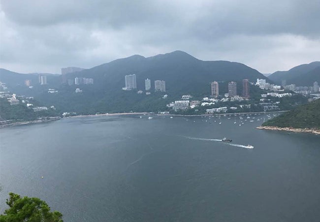 A boat moves across a lake on an overcast day in Hong Kong. 