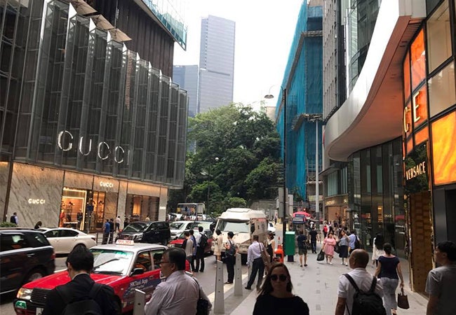 Pedestrians move across a street in Hong Kong in front of a store with several large Gucci signs. 