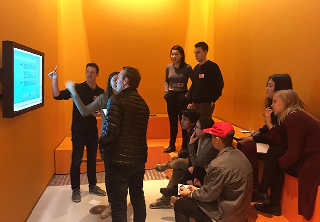 Students point to graphics displayed on a digital screen while working on a mock diplomatic exercise at the European Parliament.