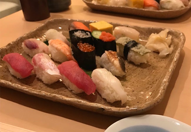 A plate of sushi arranged on a table in a low-light setting in Tokyo. 