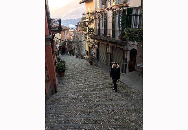 MBA student Natasha Lim stands on a quiet, winding street in the town of Bellagio, Italy. 