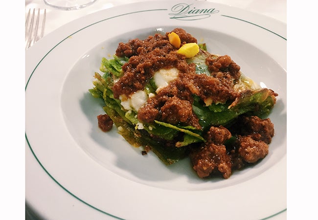 A close-up shows Italian food covered in sauce on a white plate. 