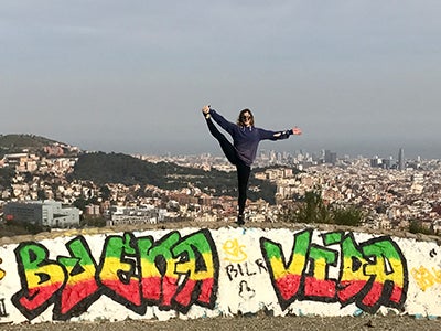 MBA student Elizabeth Cooke balances on one foot while standing in front of a scenic view of Barcelona.
