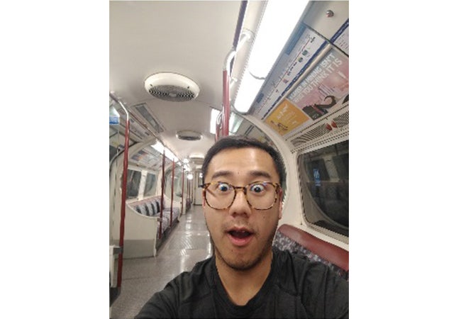 MBA student Dennis Au raises his eyebrows and takes a selfie in an empty car on the London tube. 