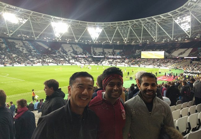 MBA student Dennis Au poses with friends during a nighttime football match between West Ham and an opponent.