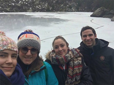 MBA student Matt Scannella poses with friends, all bundled in cold-weather gear, in front of a mountain pond called Laguna Negra. 