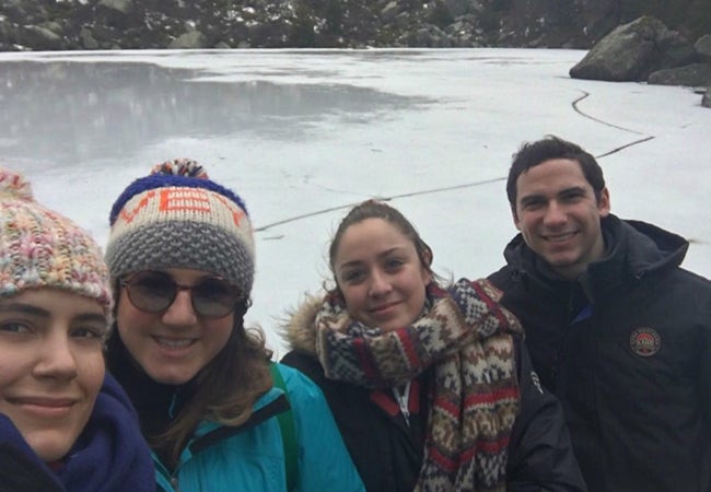 MBA student Matt Scannella poses with friends, all bundled in cold-weather gear, in front of a mountain pond called Laguna Negra. 