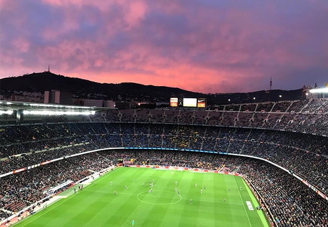 Football teams FC Barcelona and Levante UD compete in a stadium in Barcelona, Spain during sunset. 