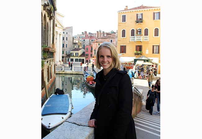 Undergraduate student Michelle Enkerlin leans over a railing above a canal. 