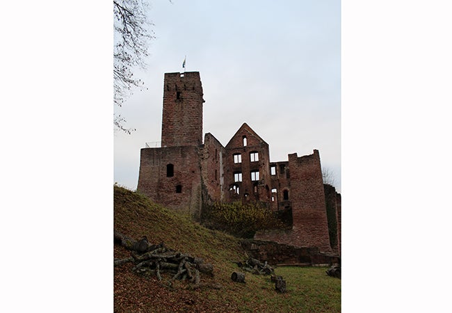 The ruins of an abandoned brick building rise up along a hillside. 