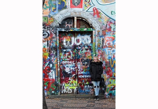 Undergraduate business student Michelle Enkerlin stands in front of a door covered in colorful graffiti while studying abroad in Germany.