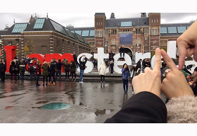 Three hands form the letter "N" to replace a portion of a sign that reads "I amsterdam" so the sign spells "I am Stern."