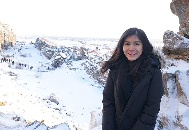 Undergraduate business student Natasha Lim smiles while standing in a snowy landscape with fellow hikers in the background. 