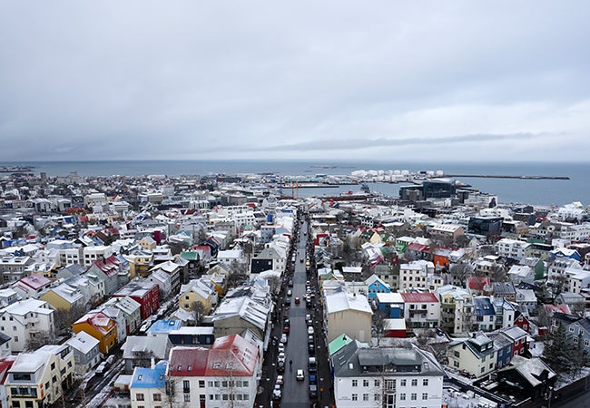 An aerial view of Reykjavik, Iceland shows a smattering of snow amongst colorful rooftops and brightly-colored homes. 