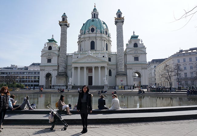 Undergraduate business student Natasha Lim stands in front of an ornately-decorated white stone building in Vienna.