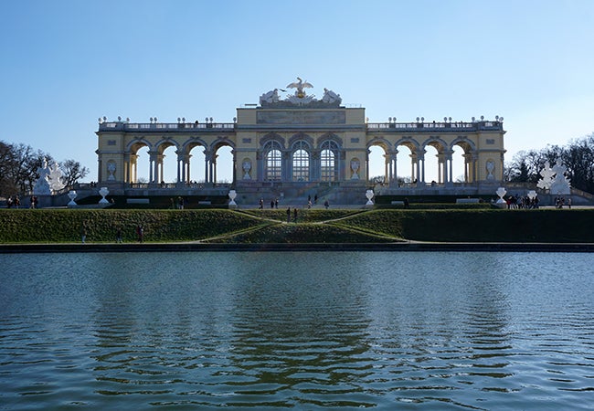 Visitors mill around the large fountain and spectacular gates in front of Schönbrunn Palace in Vienna.